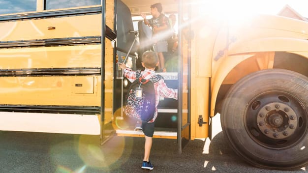 kid getting onto school bus with kid and driver already on bus