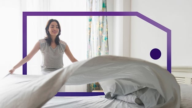 Woman making a bed, lifting a sheet in a bright, framed by a purple outlined price tag