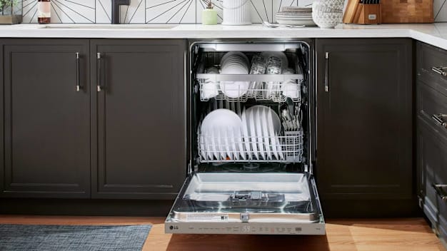 LG LDPH5554S dishwasher with door open showing white dishes and glasses, in kitchen with white countertop and dark grey cabinets