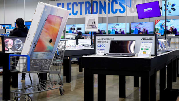 A large TV seen in a shopping cart in the electronics department of a Walmart store.