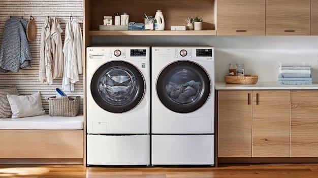 LG WM4000HWA washing machine and LG DLHC4002W dryer in laundry room with wood floor and cabinets, clothes hanging to the left of machines