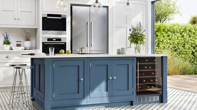 Modern kitchen with a blue island, built-in wine cooler, stainless steel appliances, and large windows overlooking a green garden.