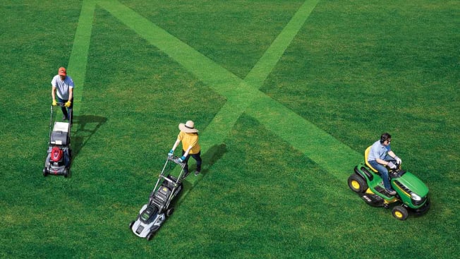 Three people pushing three different types of mowers on a lawn.