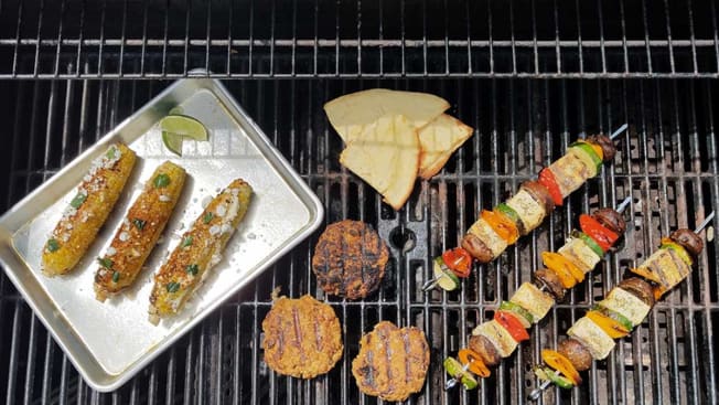A variety of plant-based foods being cooked on a gas grill