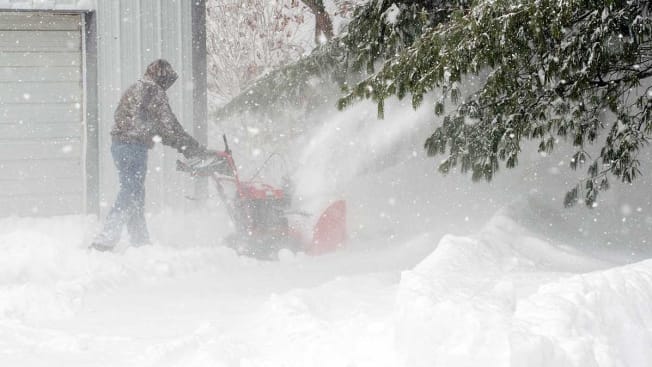 Person using snow blower in the middle of a snow storm.