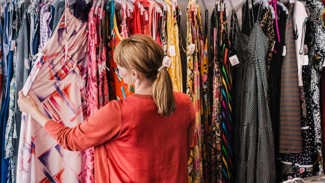 woman looking at a rack of dresses