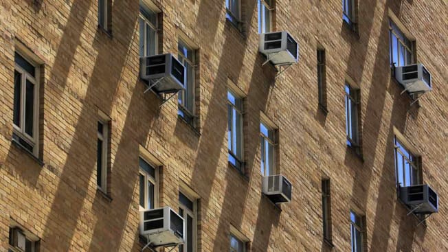 detail of exterior of brick apartment building with multiple old window air conditioner units