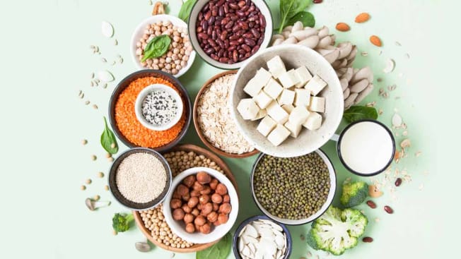 overhead view of a mix of different types of beans, tofu, spinach, and broccoli