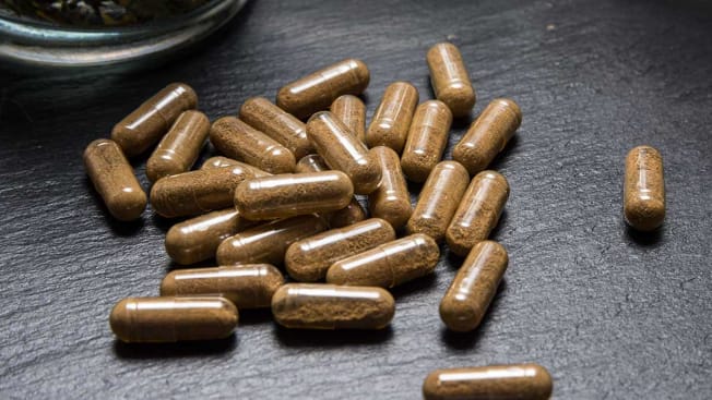 herbal supplement capsules on black surface