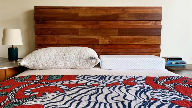 two white pillows on a bed with wooden headboard