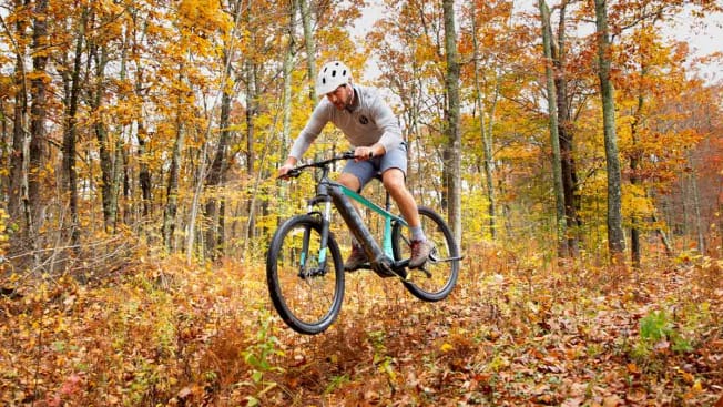 person riding Trek Powerfly 4 electric mountain bike through wooded area