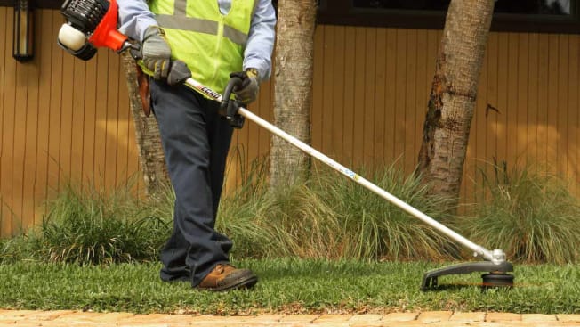 A person using the Echo SRM-2620 electric string trimmer.