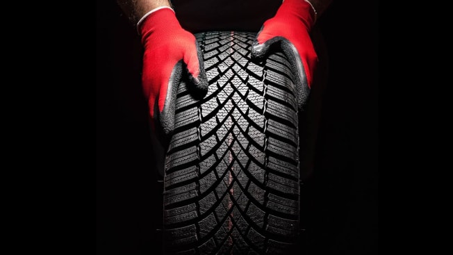 Hands wearing gloves holding onto a new tire.