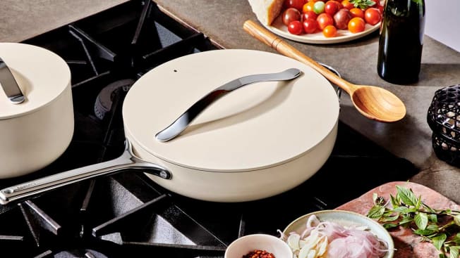 Caraway Ceramic-coated cookware on gas cooktop with tomatoes, sliced onions, and basil around cooktop
