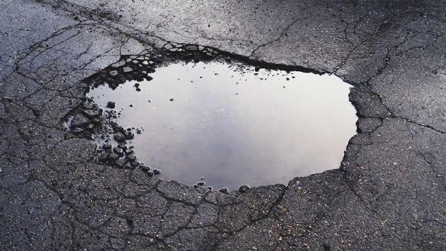A pothole in a road filled with water.