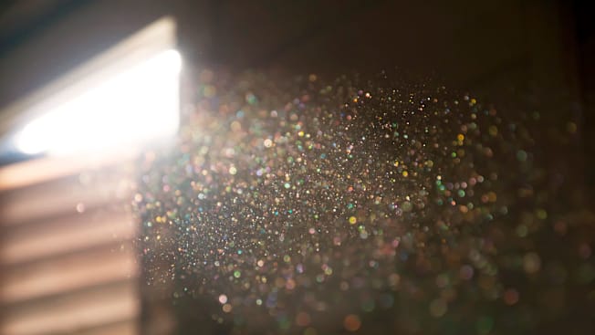 sunbeam highlighting dust particles in home with blurred window and blinds in background