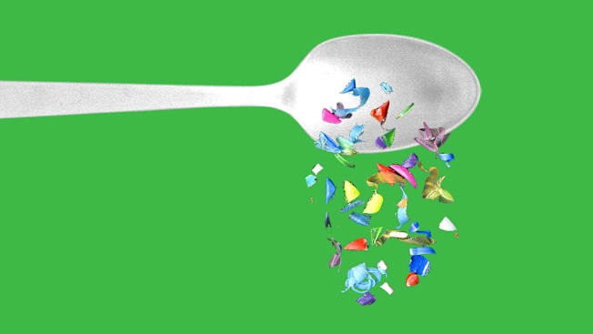 Metal spoon spilling fragments of microplastics in various colors and shapes.