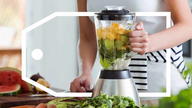 Woman using blender for smoothie with vegetables and fruits.
