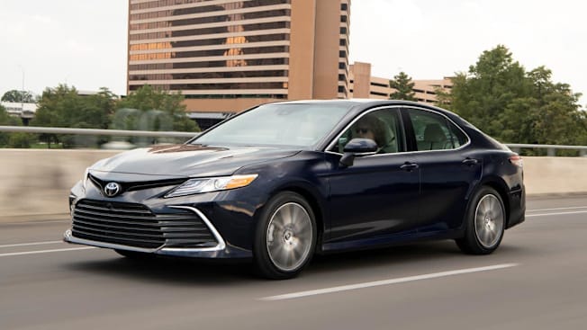 2021 Toyota Camry in black on road with building and trees in background