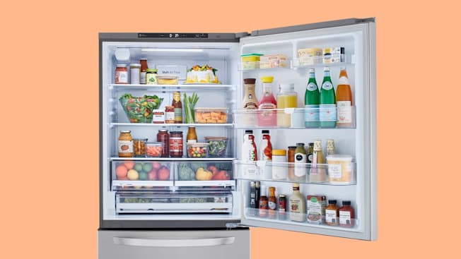 LG LRDCS2603S refrigerator with door open, showing various foods (fruits, vegetables, sodas, condiments, butter)