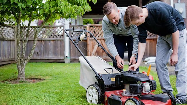 Father teaching son how to use the lawn mower.