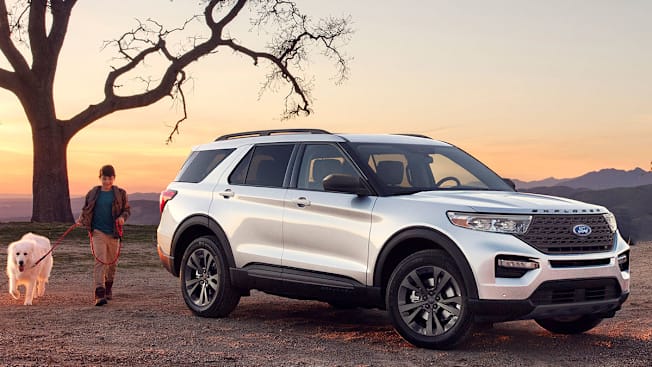 2020 Ford Explorer XLT parked near a tree at sunset with a boy and a dog.