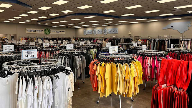 Racks of colorful clothing inside of a Goodwill store.