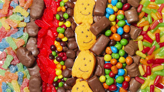 A colorful, varied assortment of candies and chocolates, including gummies, coated chocolates, and bars.
