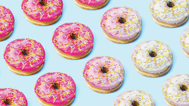 A repeating pattern of pink and white glazed donuts with colorful sprinkles on a light blue background.