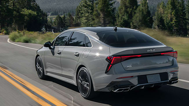 2025 Kia K5, seen from the rear driving down a road.