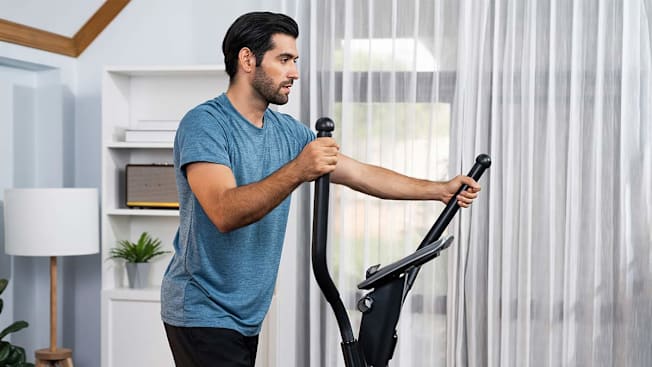 A man using an elliptical at home.