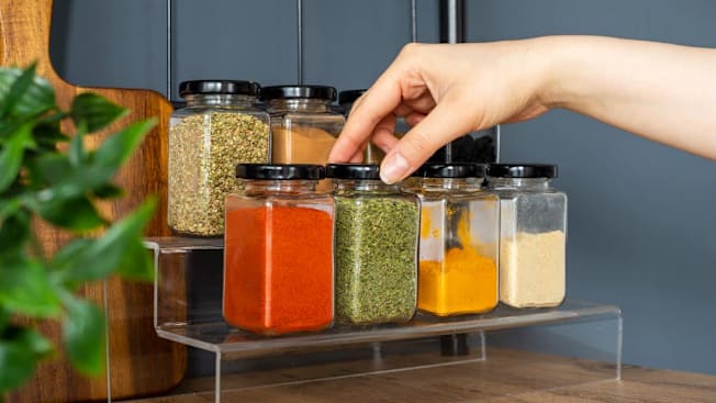 Hand reaching for spices on a spice shelf