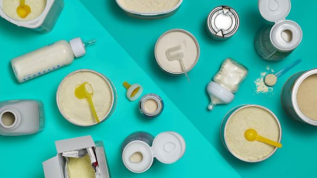 A number of liquid and powder baby formulas seen from above split between a lighter and darker shade of teal.