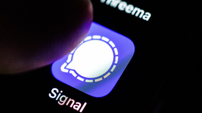 A closeup of a finger about to press the Signal app on a cell phone.