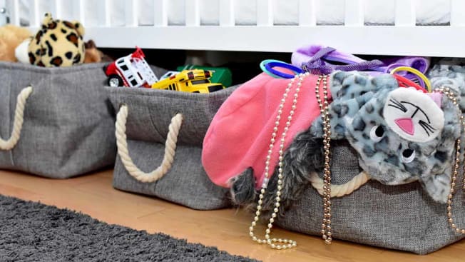 grey cloth storage baskets filled with toys under bed