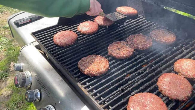Paul Hope Grilling multiple burgers on a gas grill.