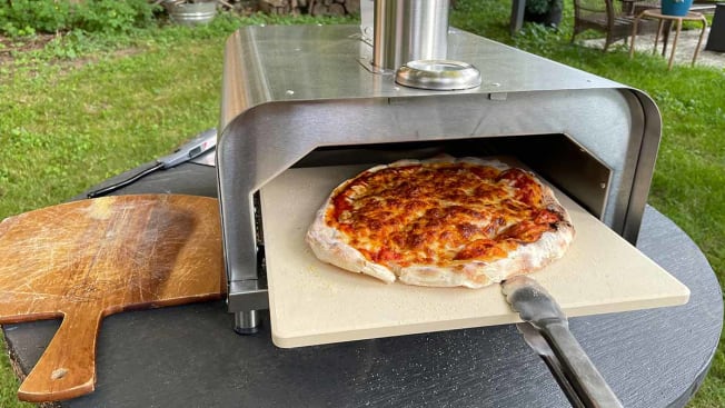 A finished pizza being slid out of the Gyber pizza oven.