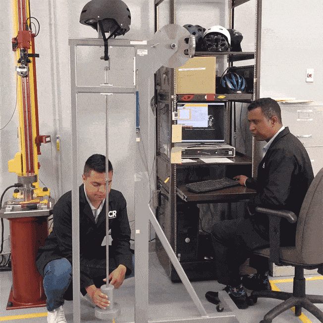 gif of two technicians testing bike helmet chin strap durability