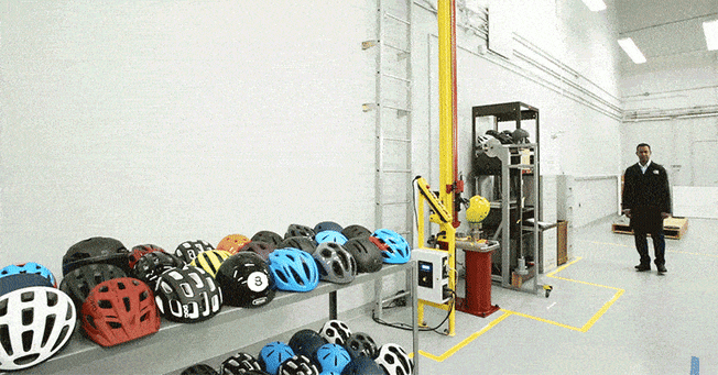 gif of bike helmet lab with helmets, test equipment, and dancing technician