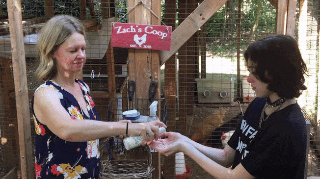 Woman giving person hand sanitizer in from of Zach's chicken coop