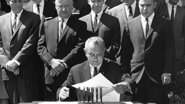 President Lyndon B. Johnson signs auto and highway safety act.