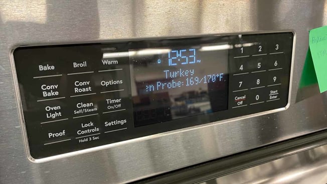 Display on an oven shows the internal temperature of a turkey cooking inside of it.