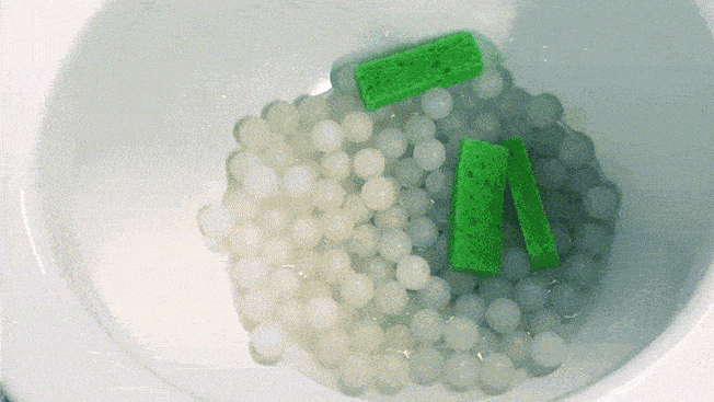 toilet being flushed with sponges, water filled condom, and white plastic balls