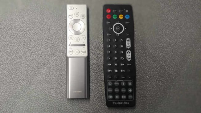 two different remotes to outdoor TVs on grey surface