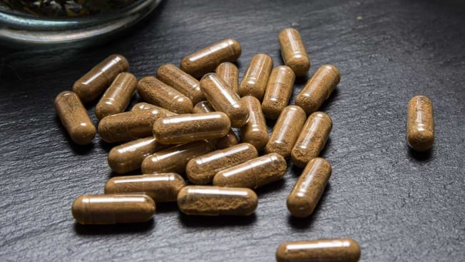 herbal supplement capsules on black surface
