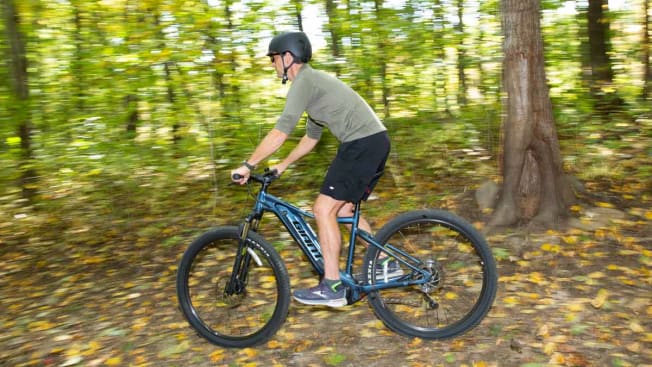 person riding Giant Talon E+ through wooded area