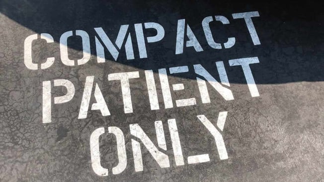 sign on asphalt that says "compact patient only"
