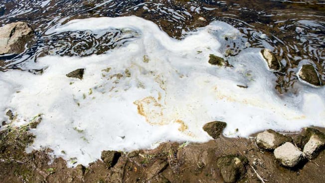 In this June 7, 2018 photo, PFAS foam gathers at the the Van Etten Creek dam in Oscoda Township, Mich., near Wurtsmith Air Force Base. Wisconsin Attorney General Josh Kaul has filed a lawsuit against Johnson Controls and Tyco Fire Products over PFAS pollution in northeastern Wisconsin.