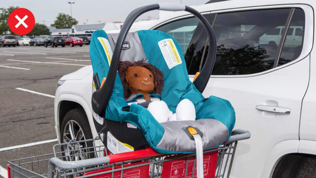 An infant carseat incorrectly placed on the toddler seat of a grocery cart.