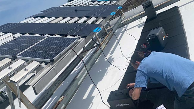 A Consumer Reports tester testing portable power stations on a rooftop